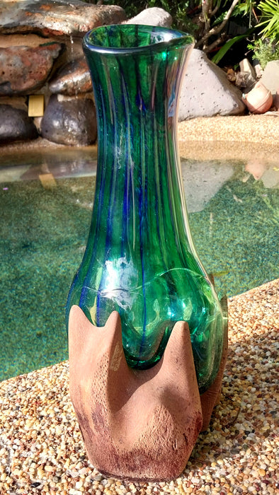 Molten teal blue and green mouthblown glass vase in timber stand.