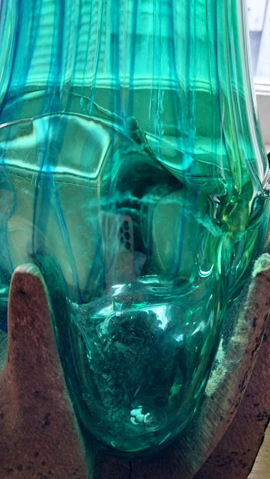 Molten teal blue and green mouthblown glass vase in timber stand.